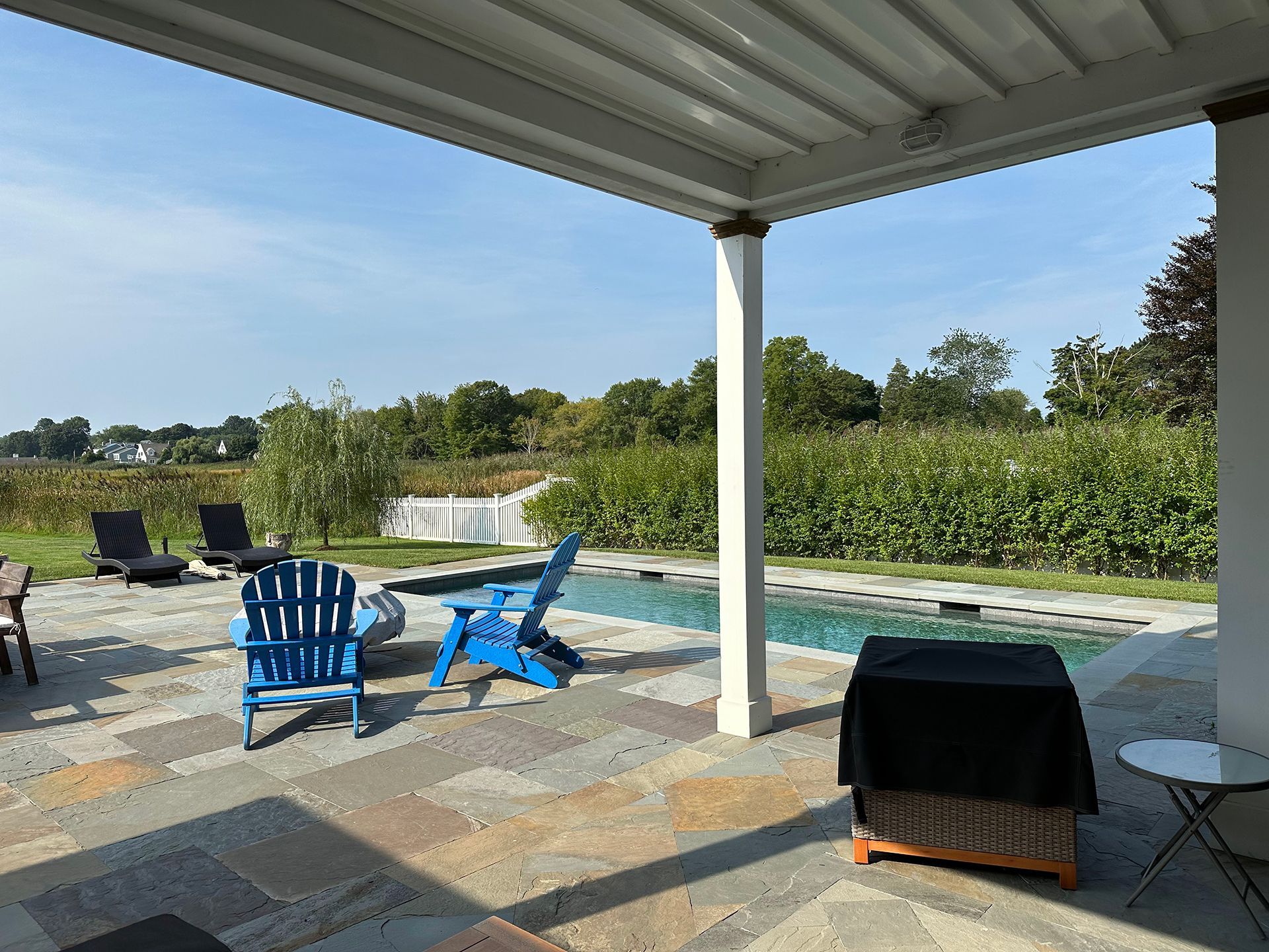 A patio with chairs and a table next to a pool.