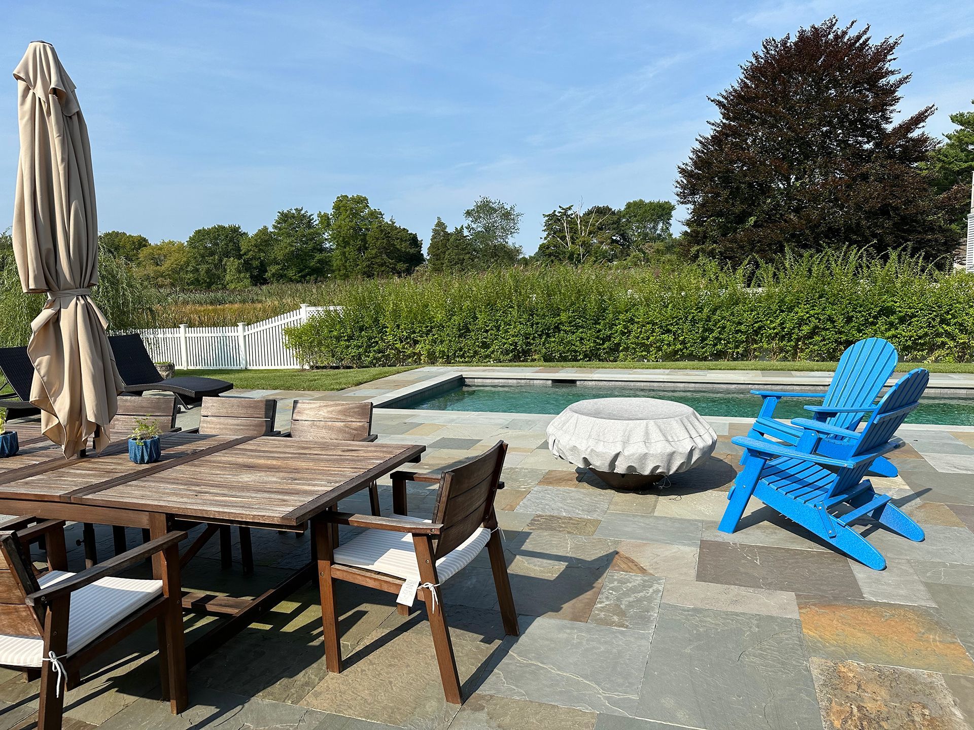 A patio with a table and chairs next to a pool.