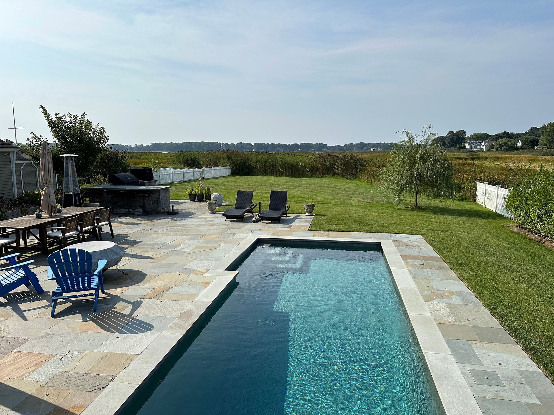 A large swimming pool surrounded by chairs and a table