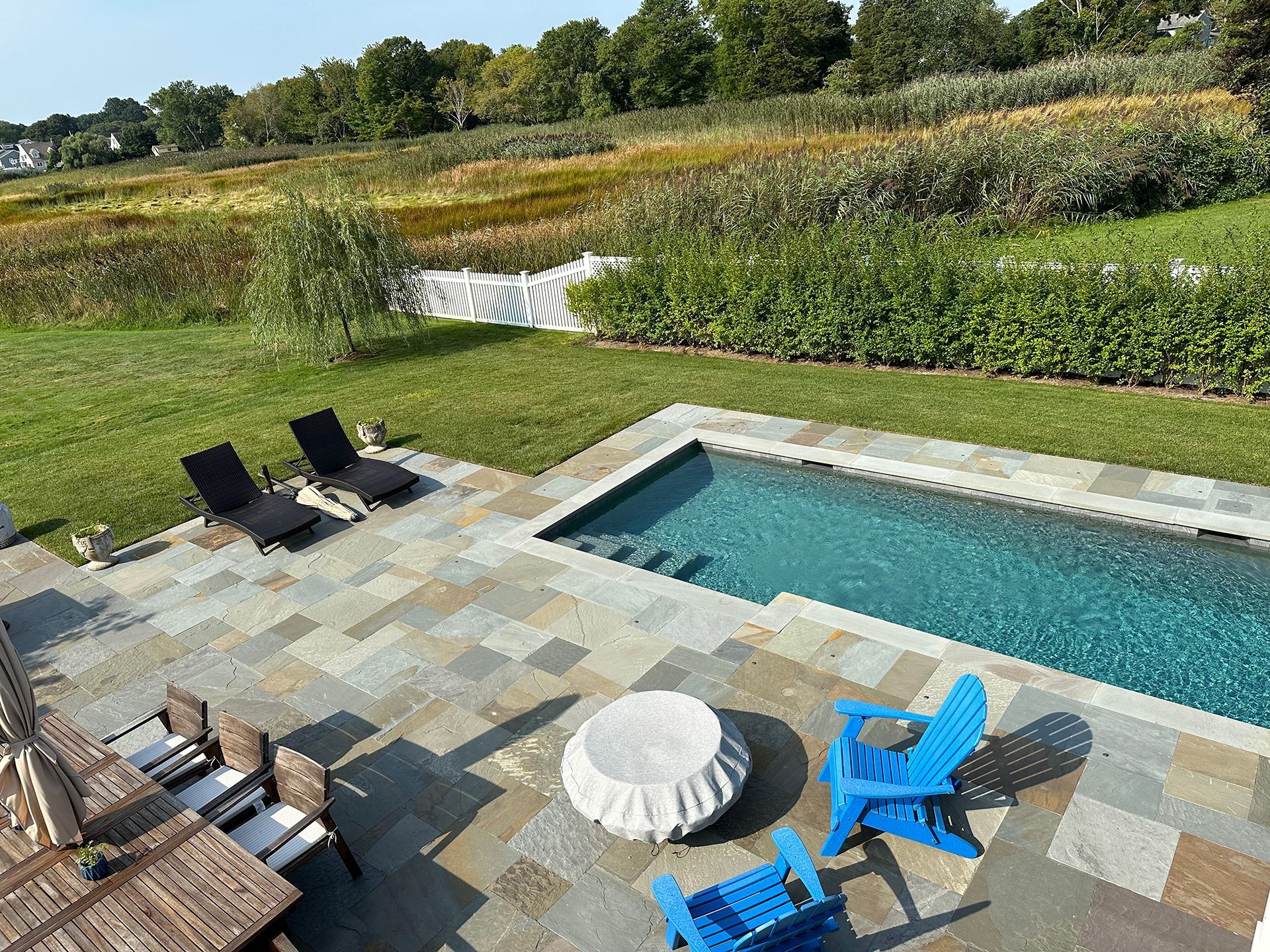 A large swimming pool is surrounded by a lush green field.