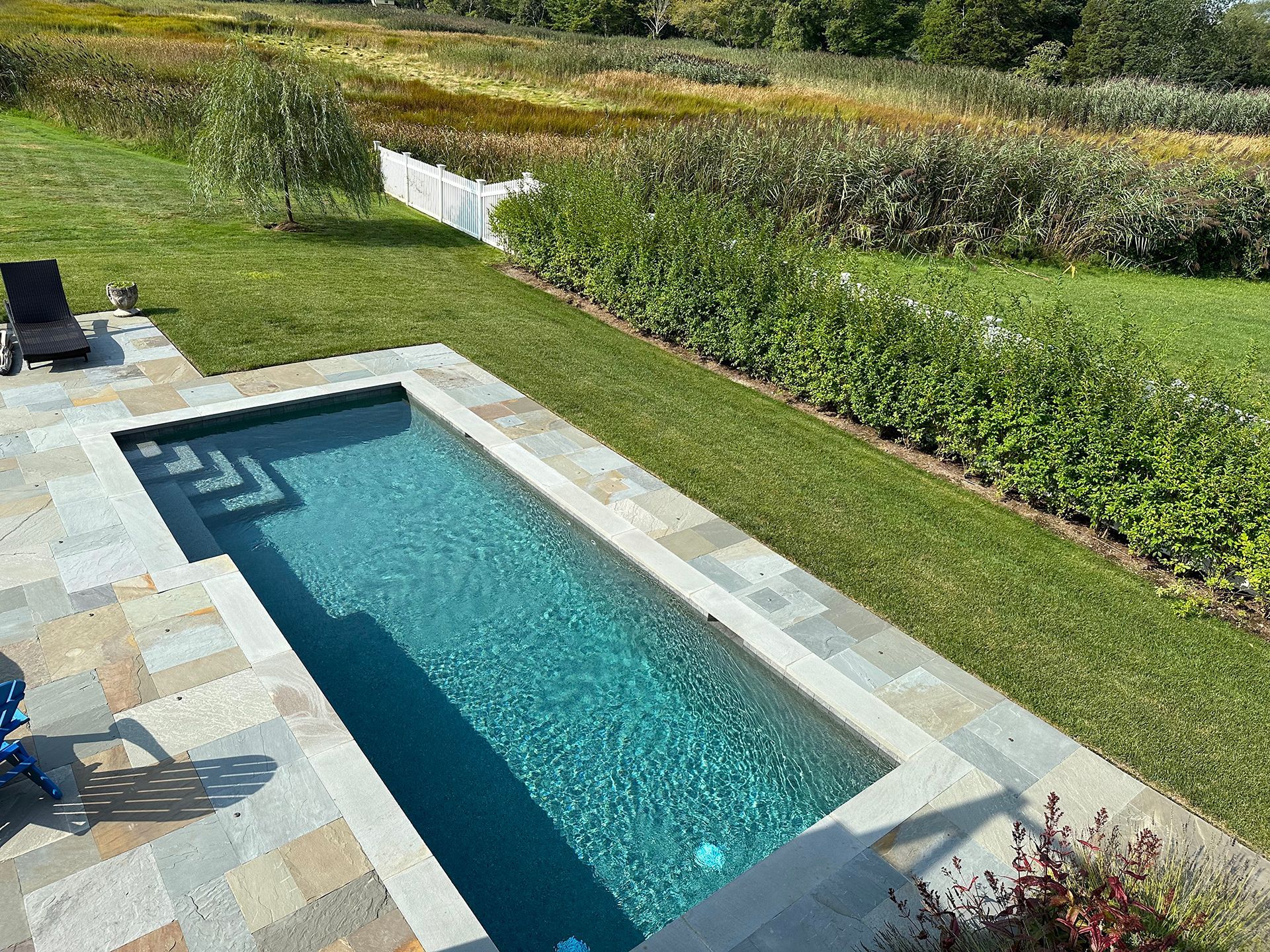 There is a swimming pool in the middle of a lush green field.