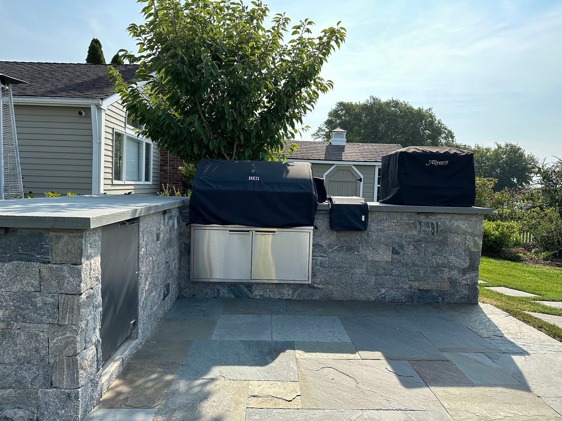 There is a grill in the backyard of a house.