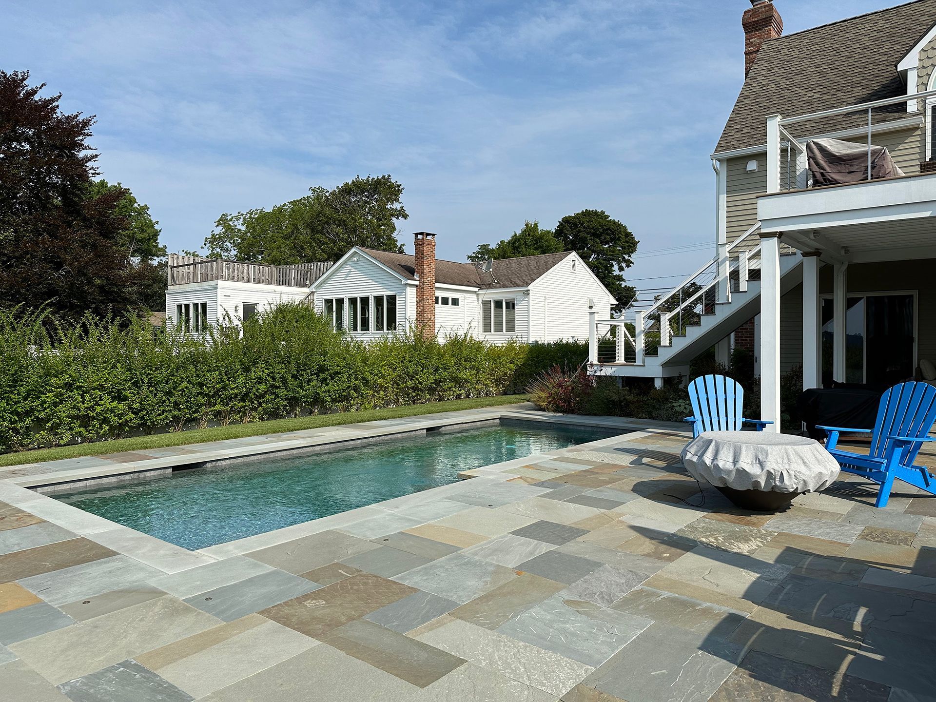 A large swimming pool is in the backyard of a house
