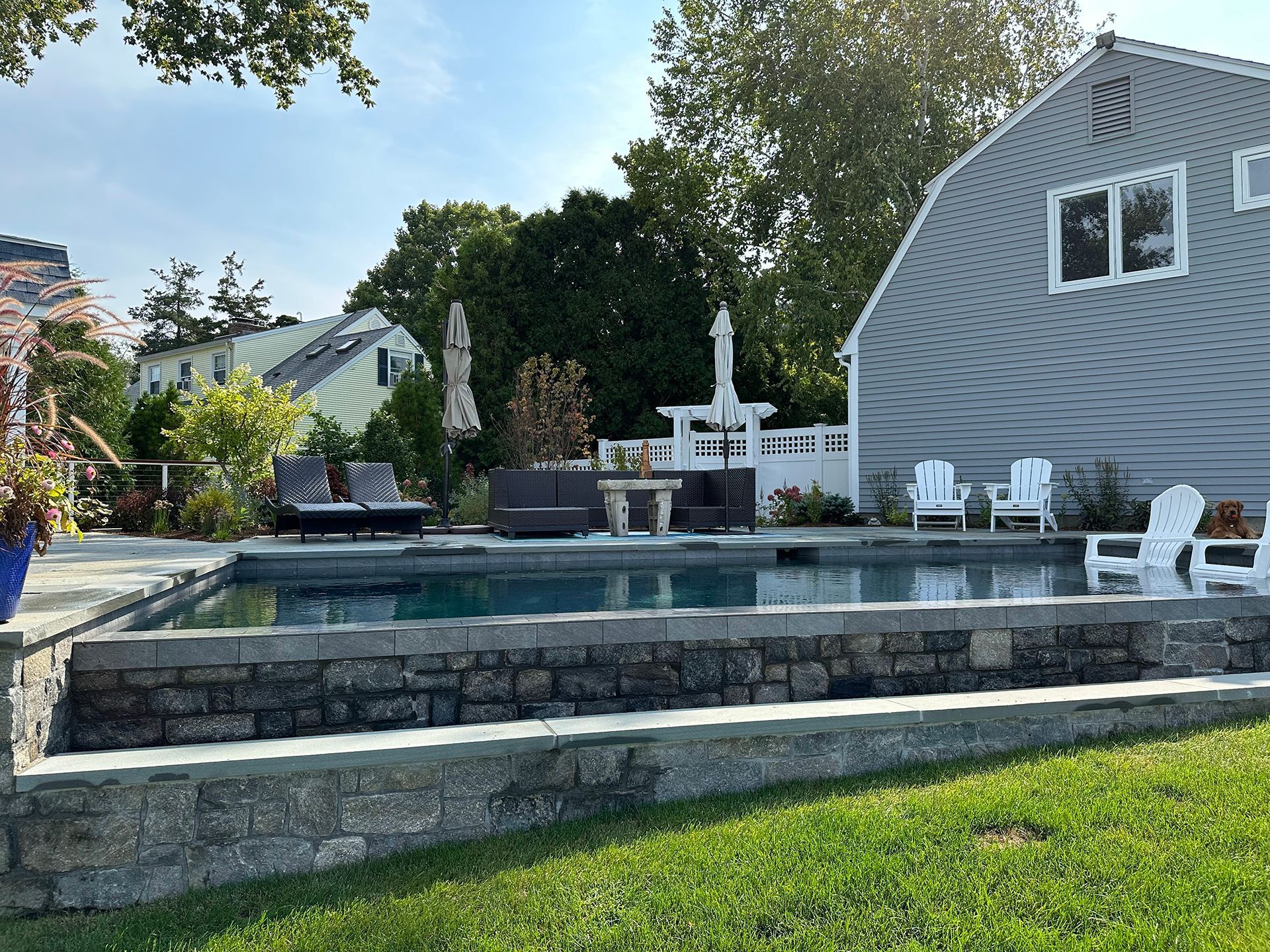 There is a large swimming pool in the backyard of a house.