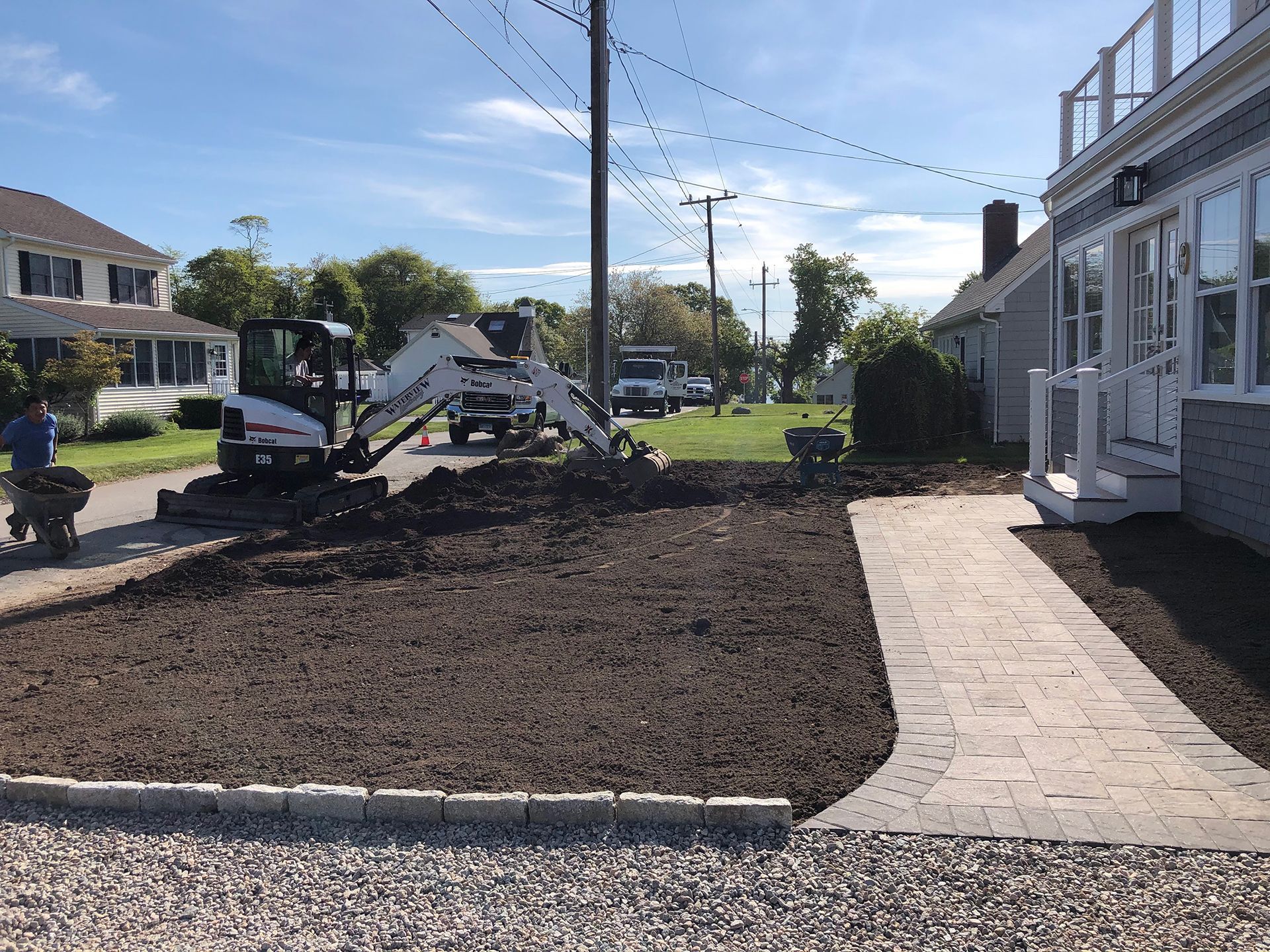 A small excavator is sitting in front of a house.