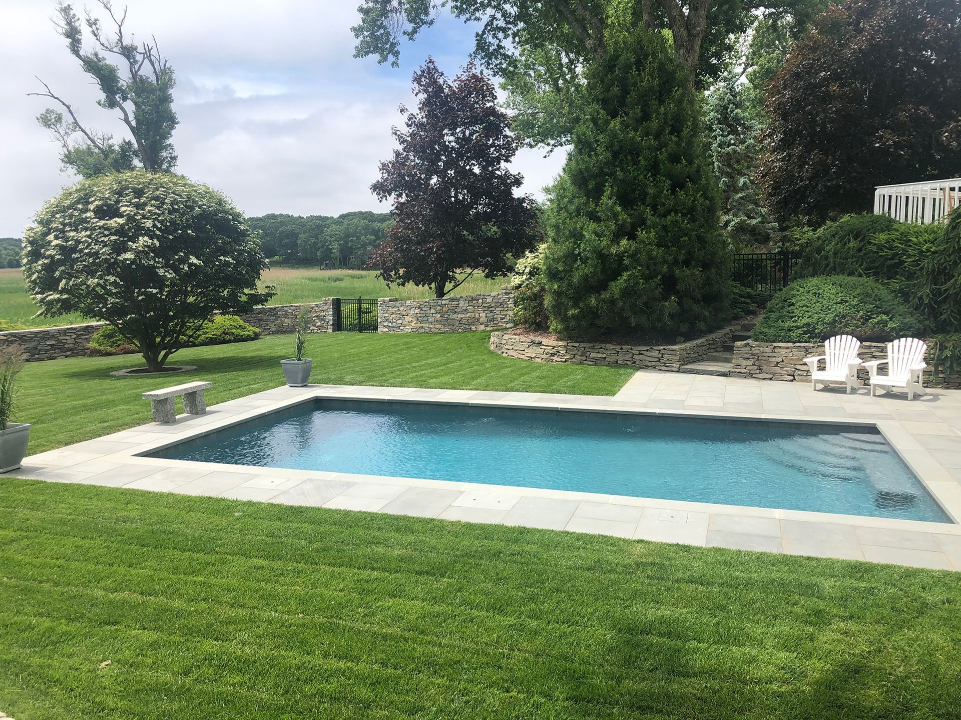 There is a large swimming pool in the middle of a lush green field.