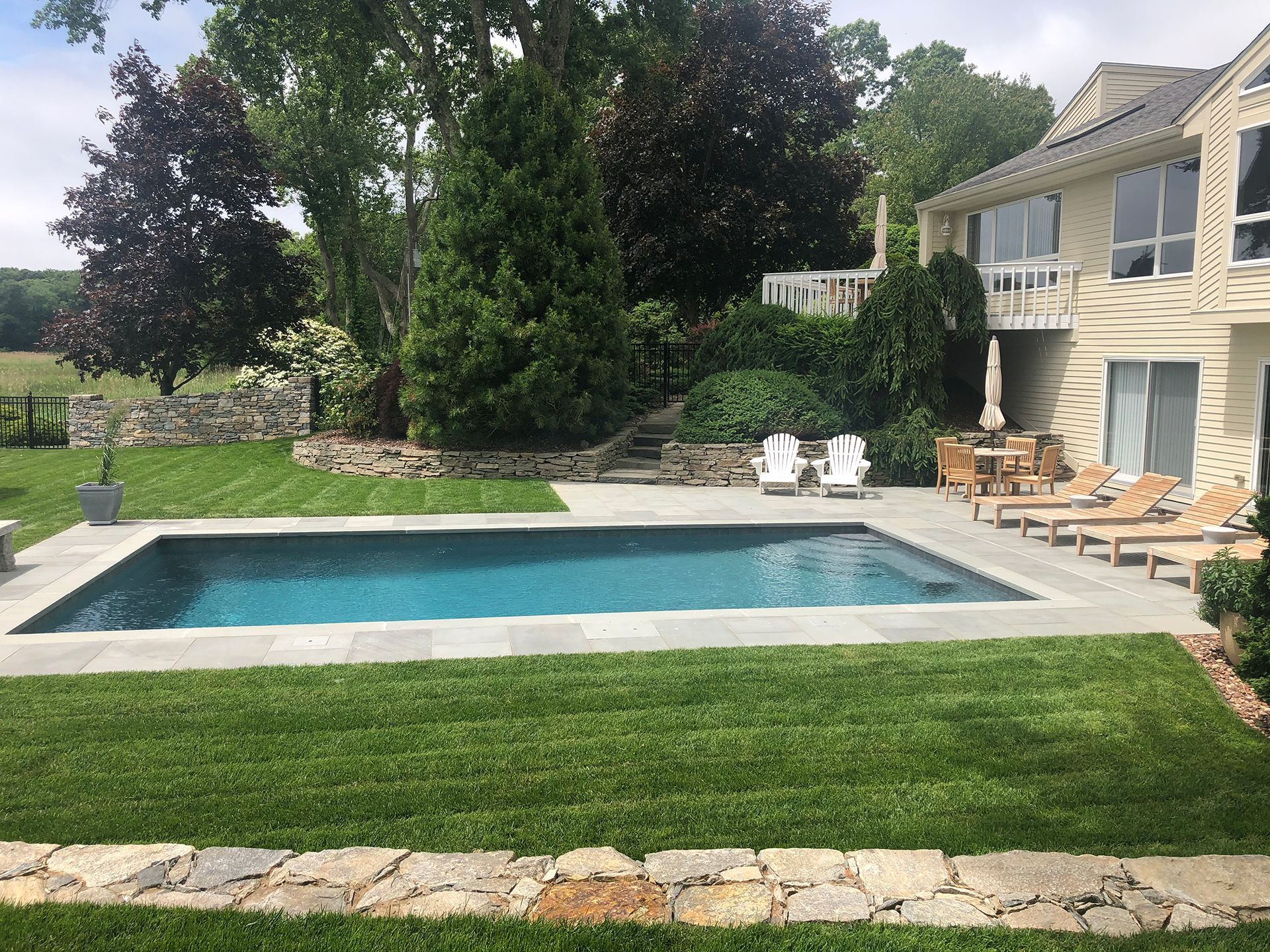 There is a large swimming pool in the backyard of a house.
