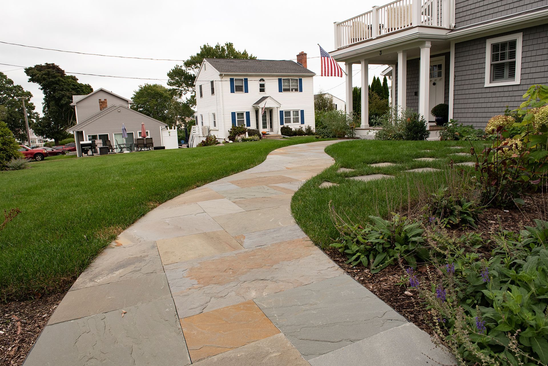 A walkway leading to a house with an american flag on the porch