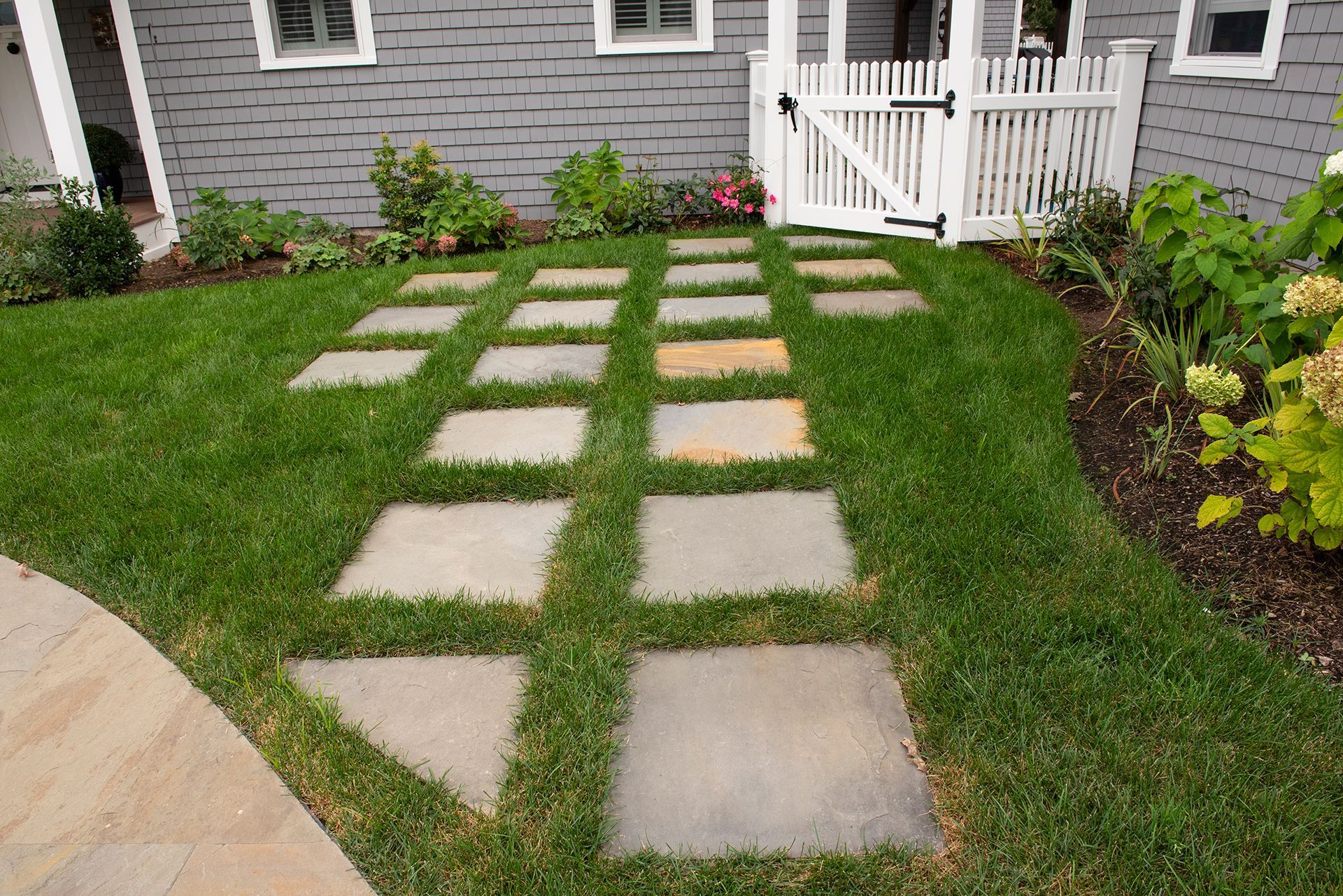 A lawn with a walkway and a gate in front of a house.