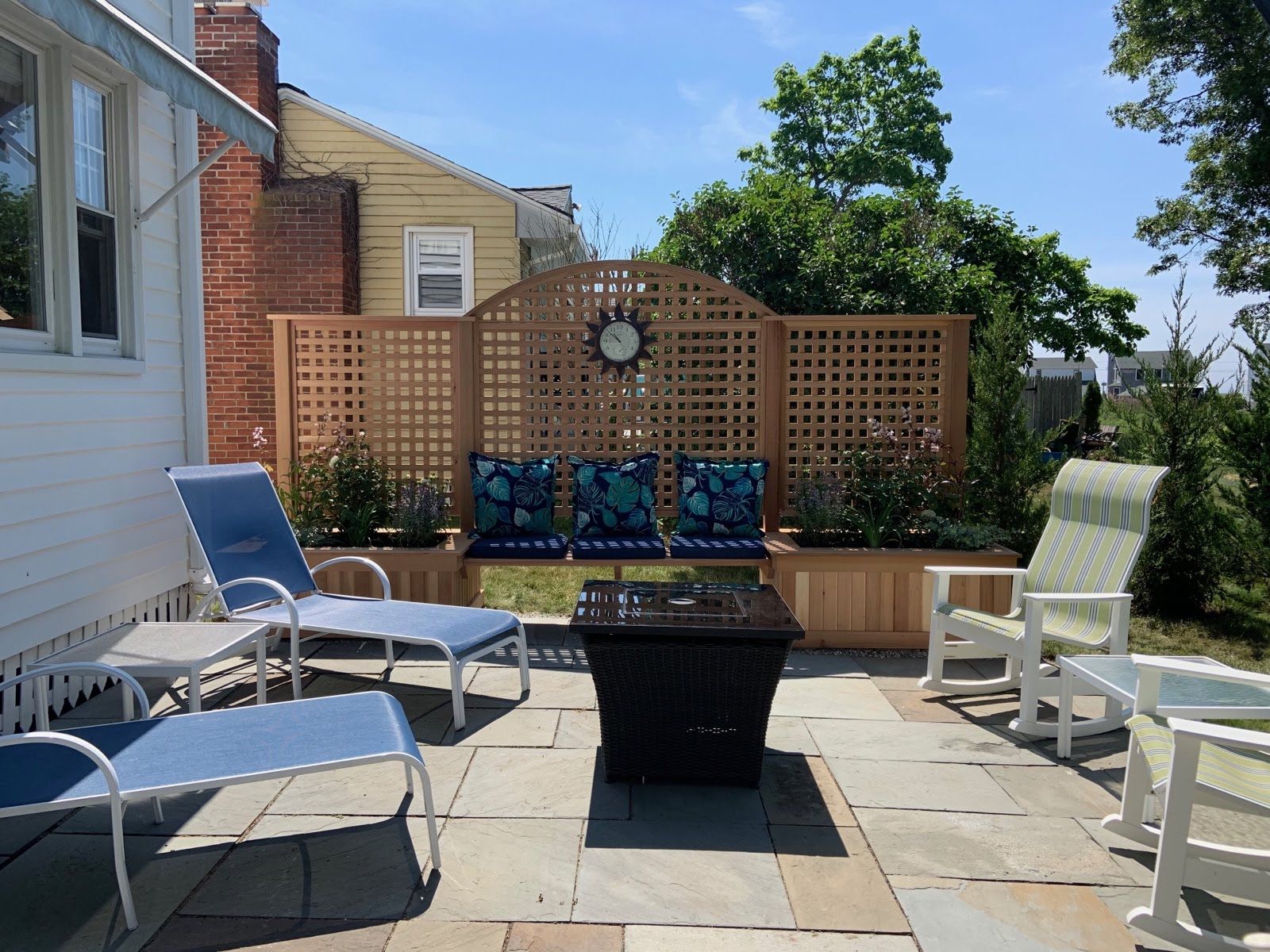 A patio with chairs and a fire pit in front of a house