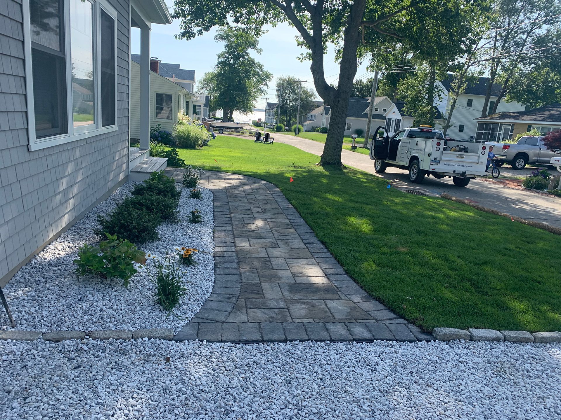 A white truck is parked in front of a house next to a walkway.