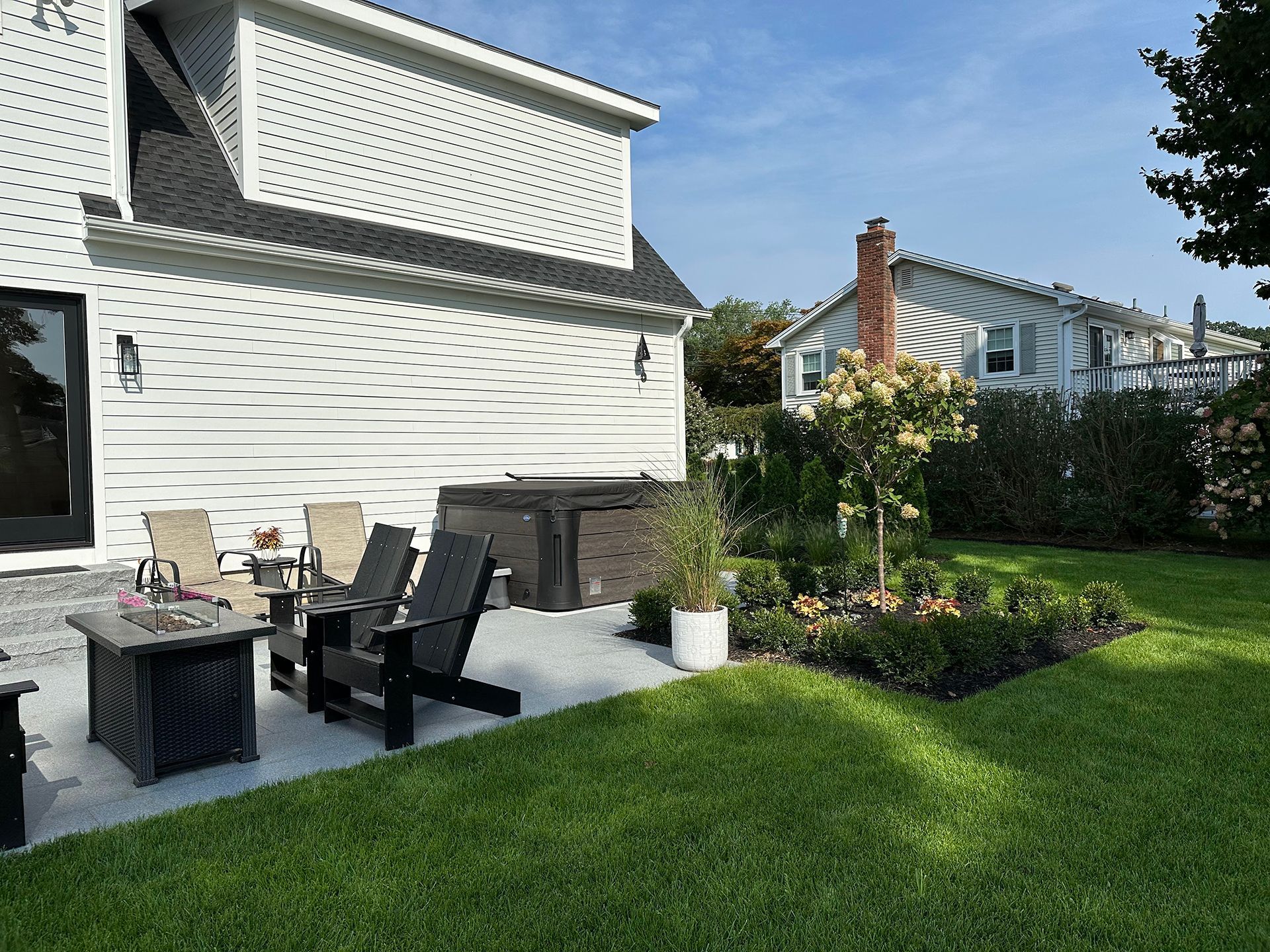 A patio with chairs and a fire pit in the backyard of a house.