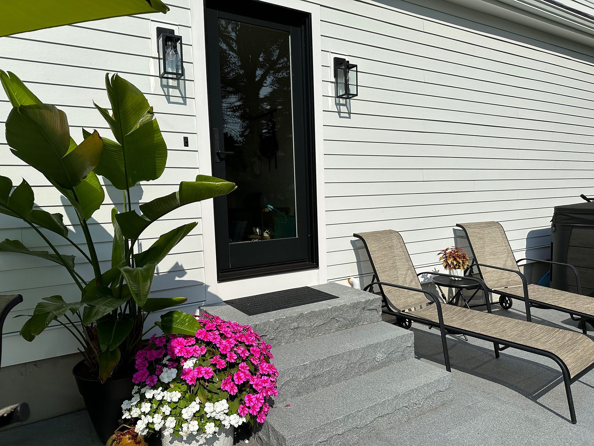 A patio with chairs and flowers in front of a house.