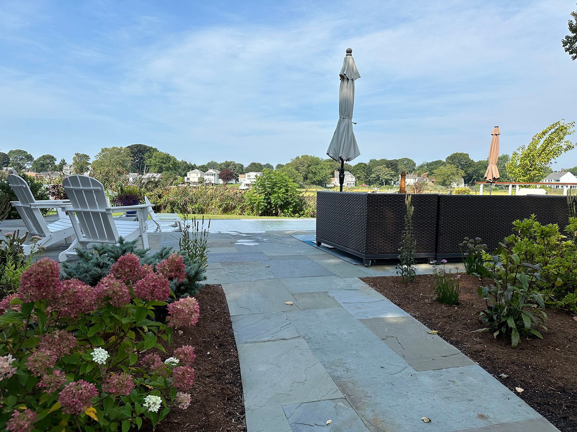 A walkway leading to a swimming pool with chairs and umbrellas