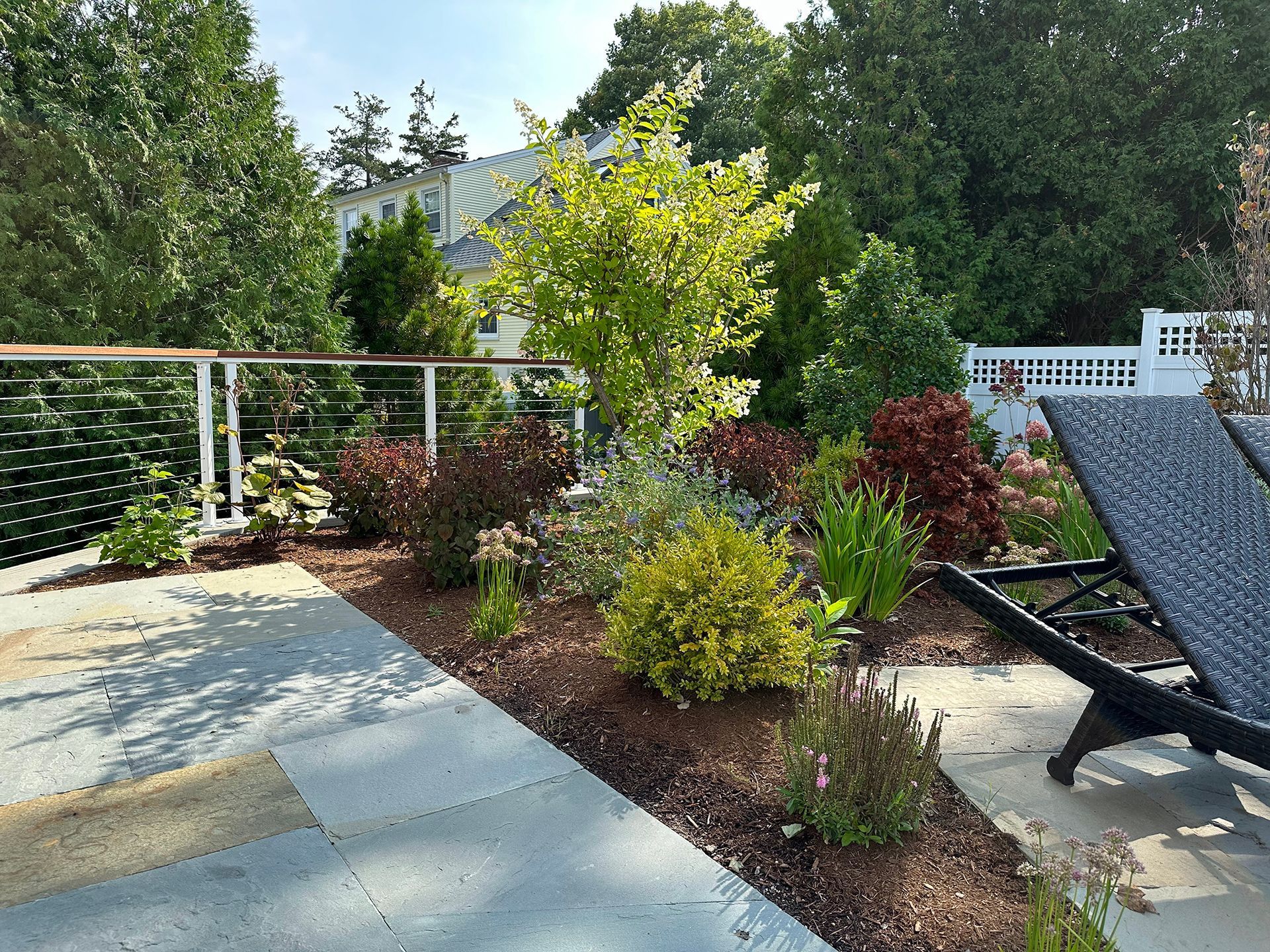 A patio with a few chairs and trees in the background.