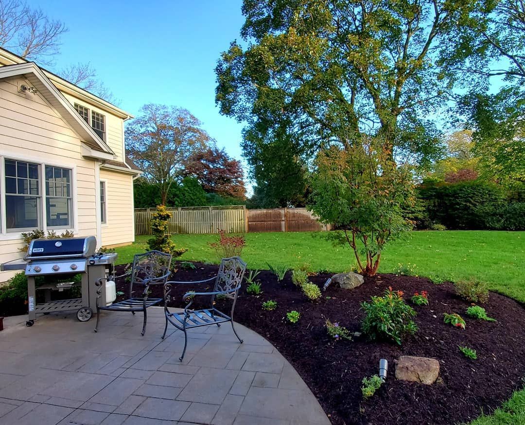 A patio with a grill and chairs in front of a house