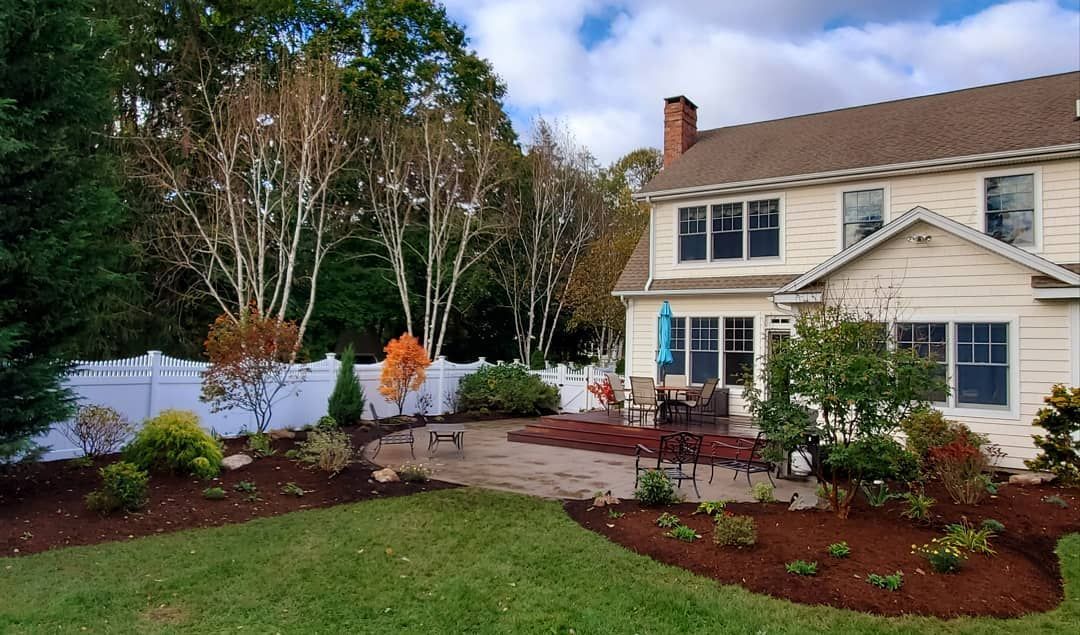 A large white house with a patio in front of it surrounded by trees