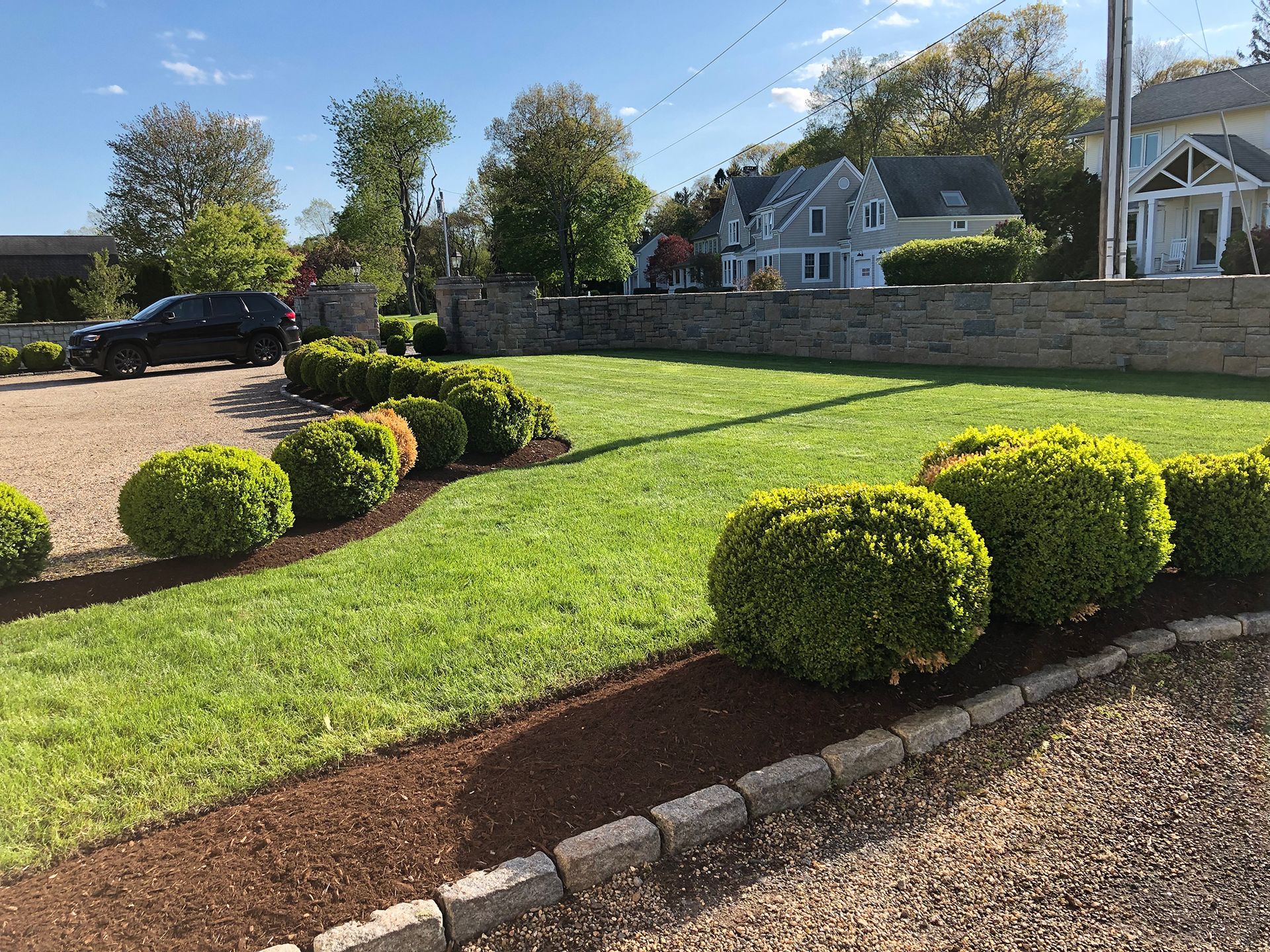 A car is parked in a driveway next to a lush green lawn.