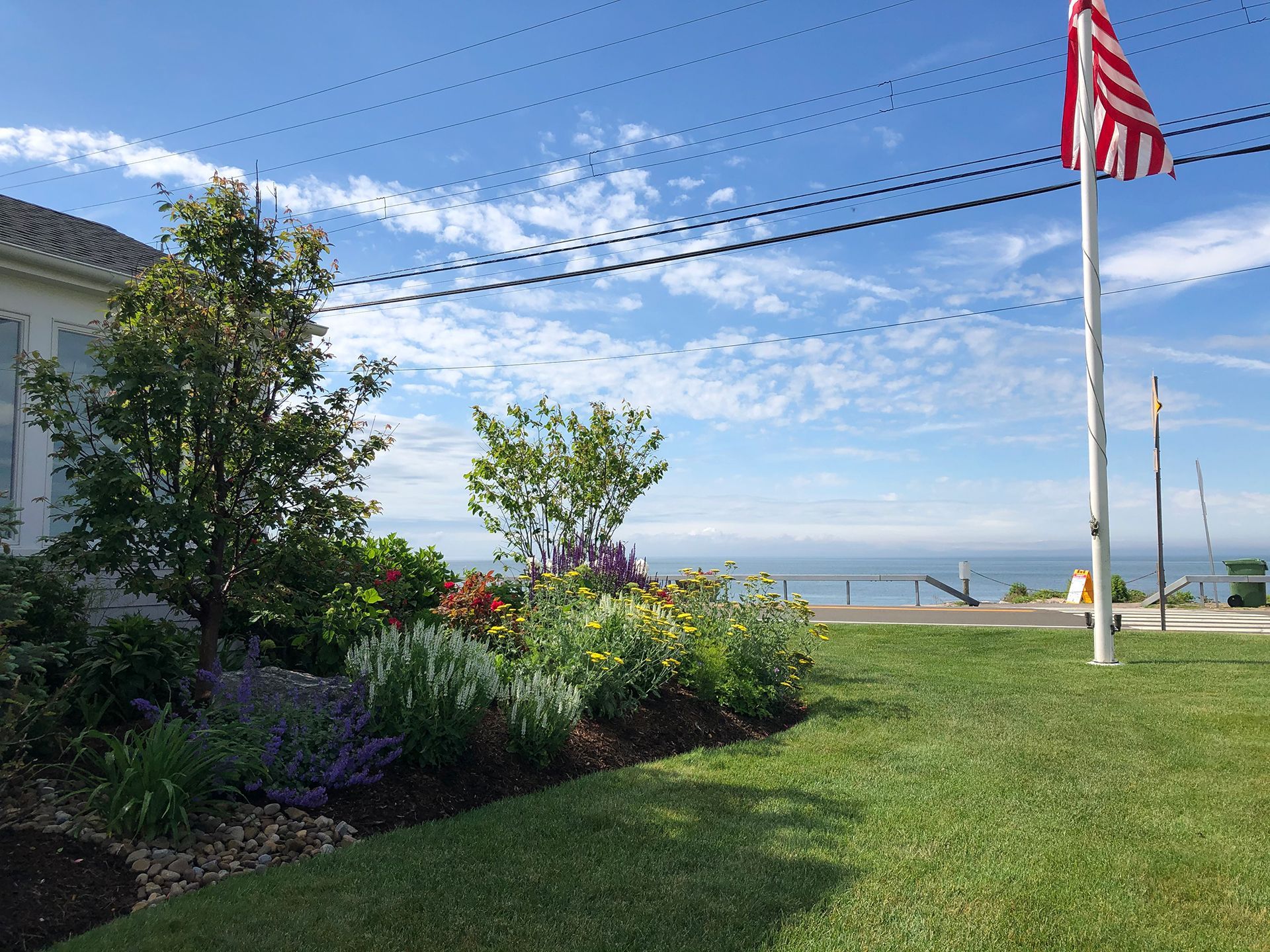 An american flag is flying in front of a house with a view of the ocean