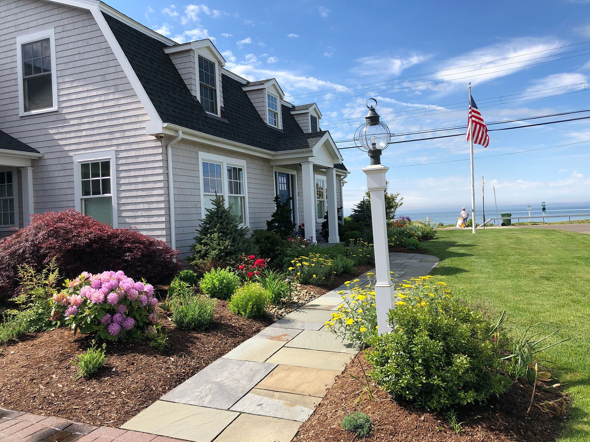 A house with a walkway leading to it and a flag in the background.