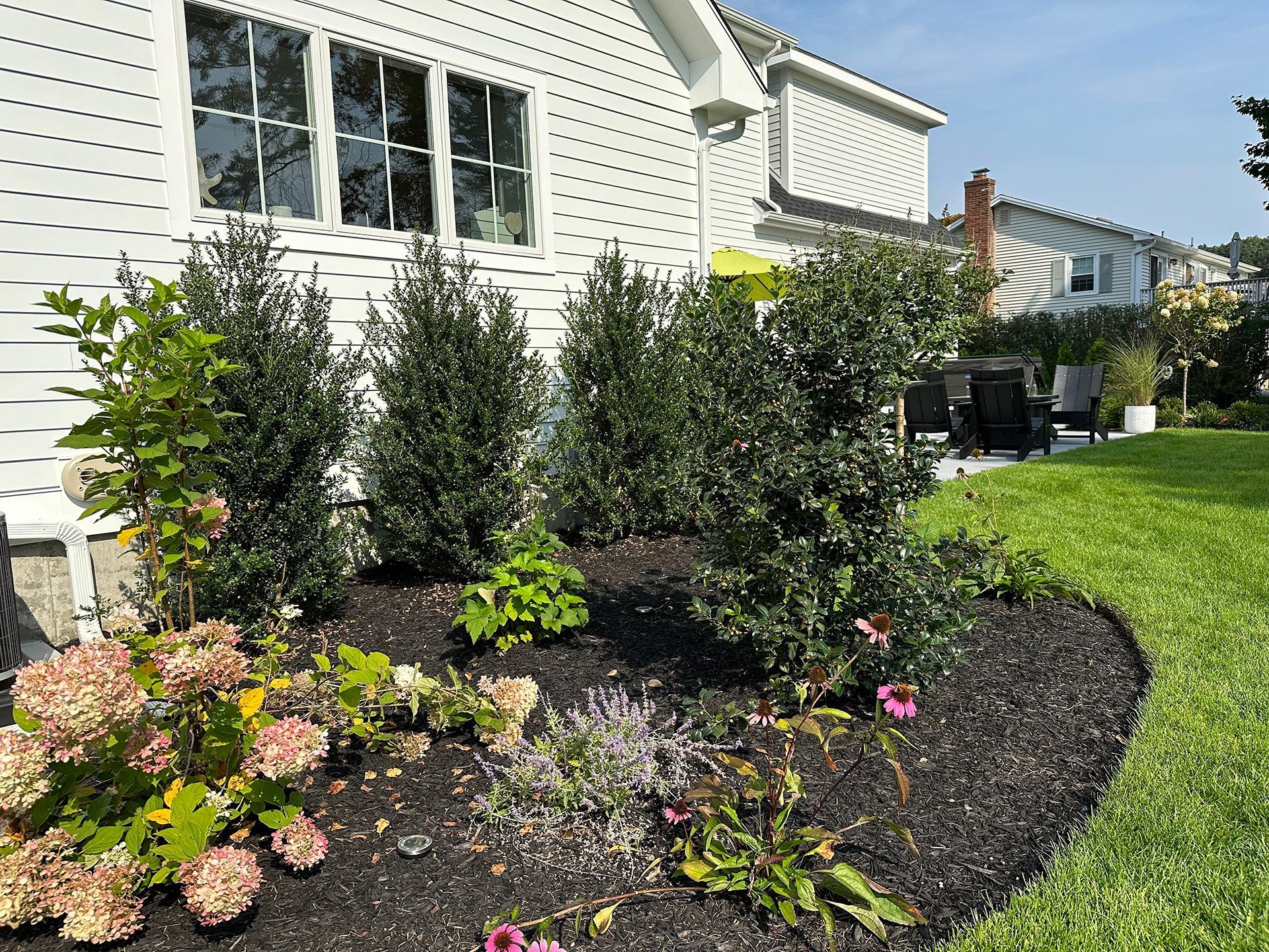 A white house with a garden in front of it.