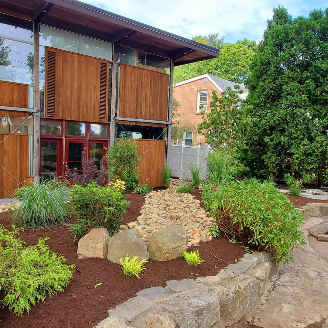a house with a lot of plants and rocks in front of it