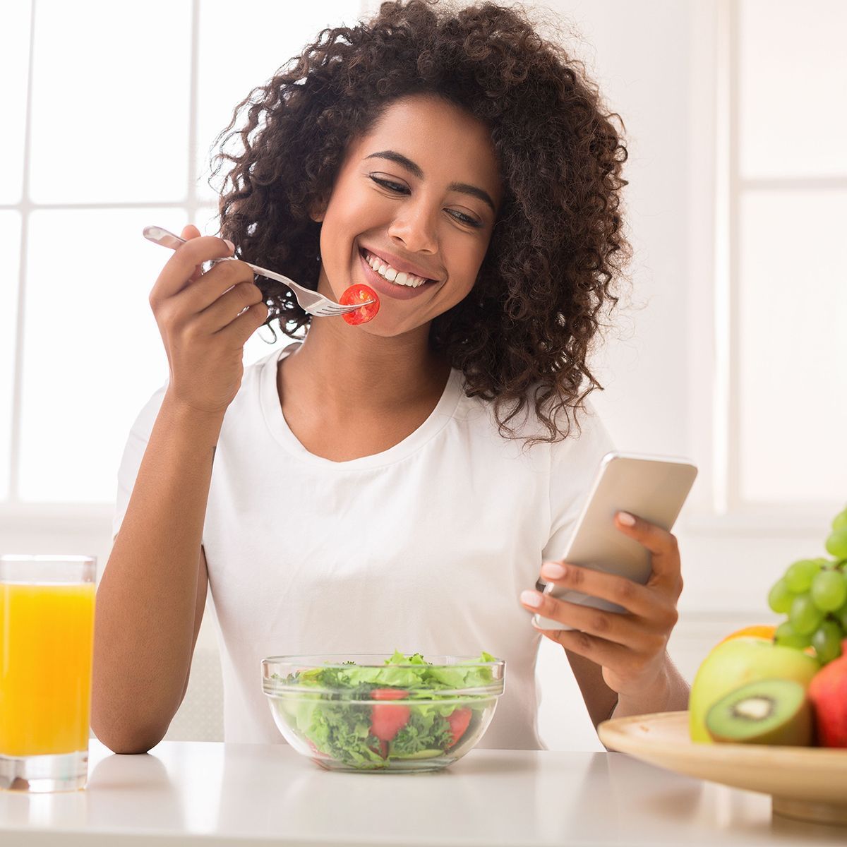 a woman is eating a salad while looking at her phone