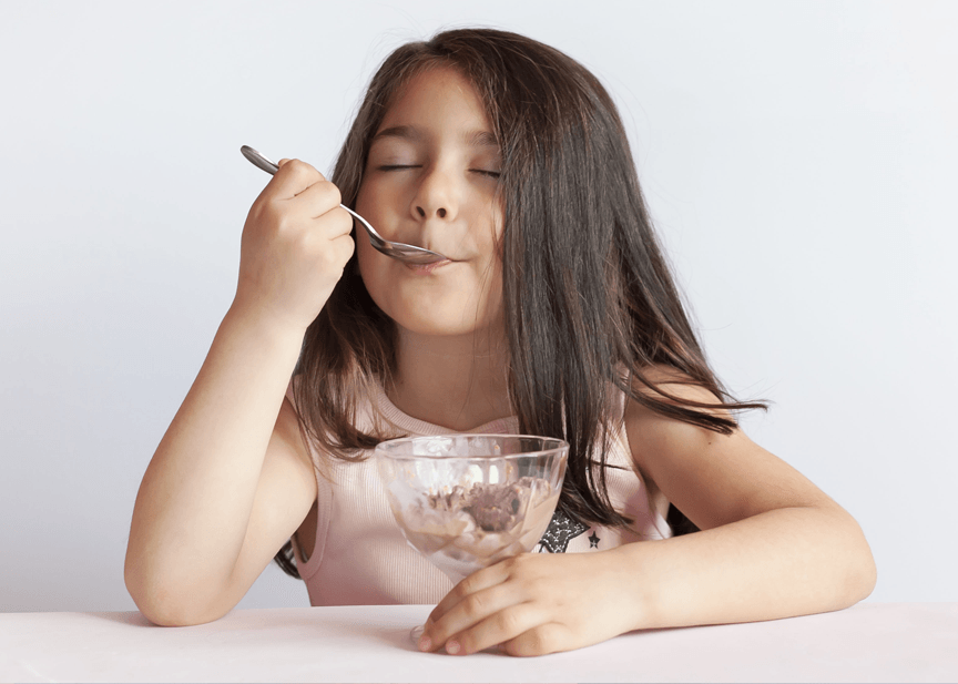 A little girl is eating ice cream from a bowl with a spoon