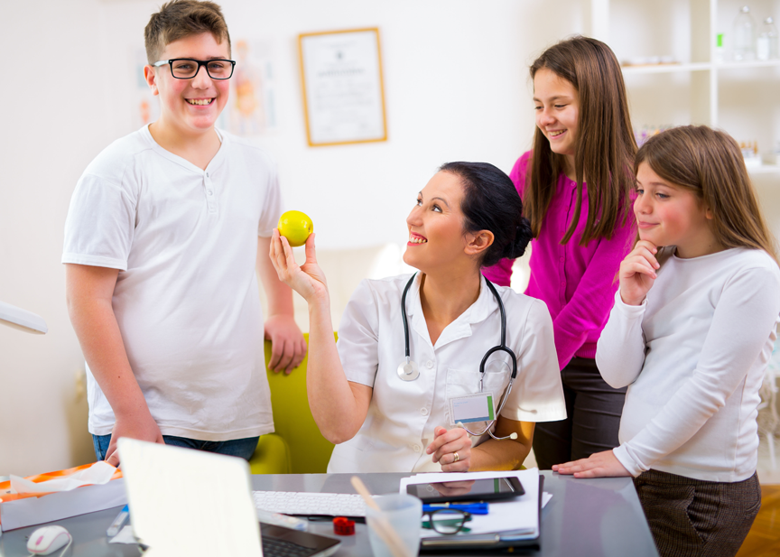 A doctor is talking to a group of children in a doctor's office