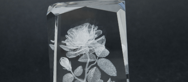 Laser engraving flower inside of the glass on a gray background.