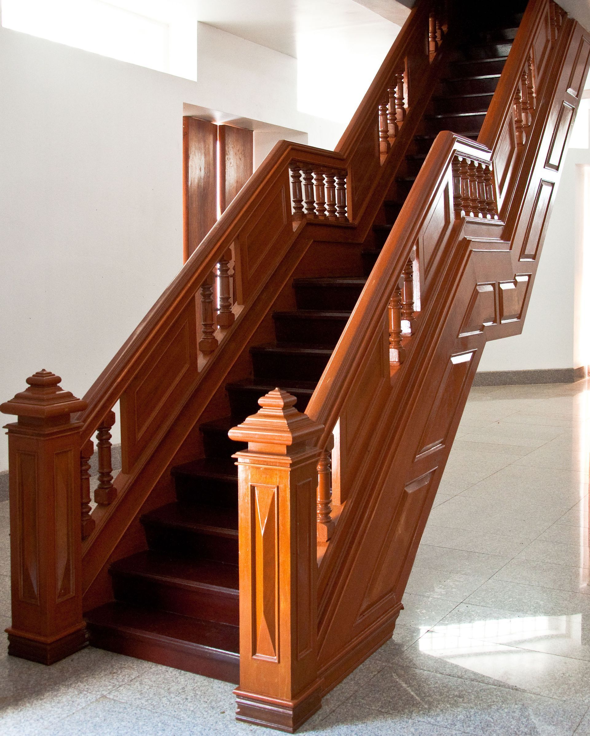 Wooden staircase with dark brown steps and banisters, ornate design. Bright interior.