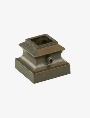 Square bronze stair post base with an opening at the top and a small hole on the side.