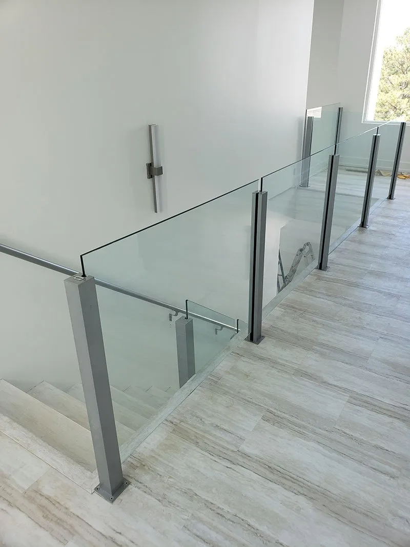 Glass and metal railing along staircase. White walls, wood-look flooring.