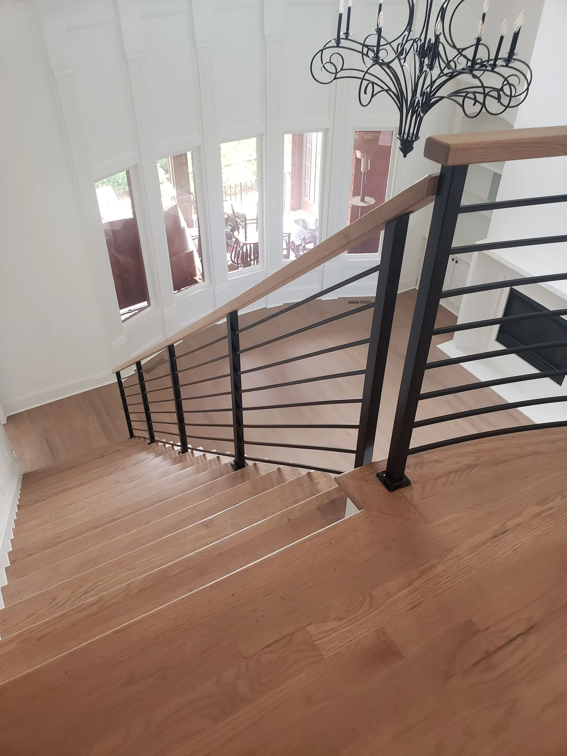 Wooden staircase with black metal railings and a chandelier.