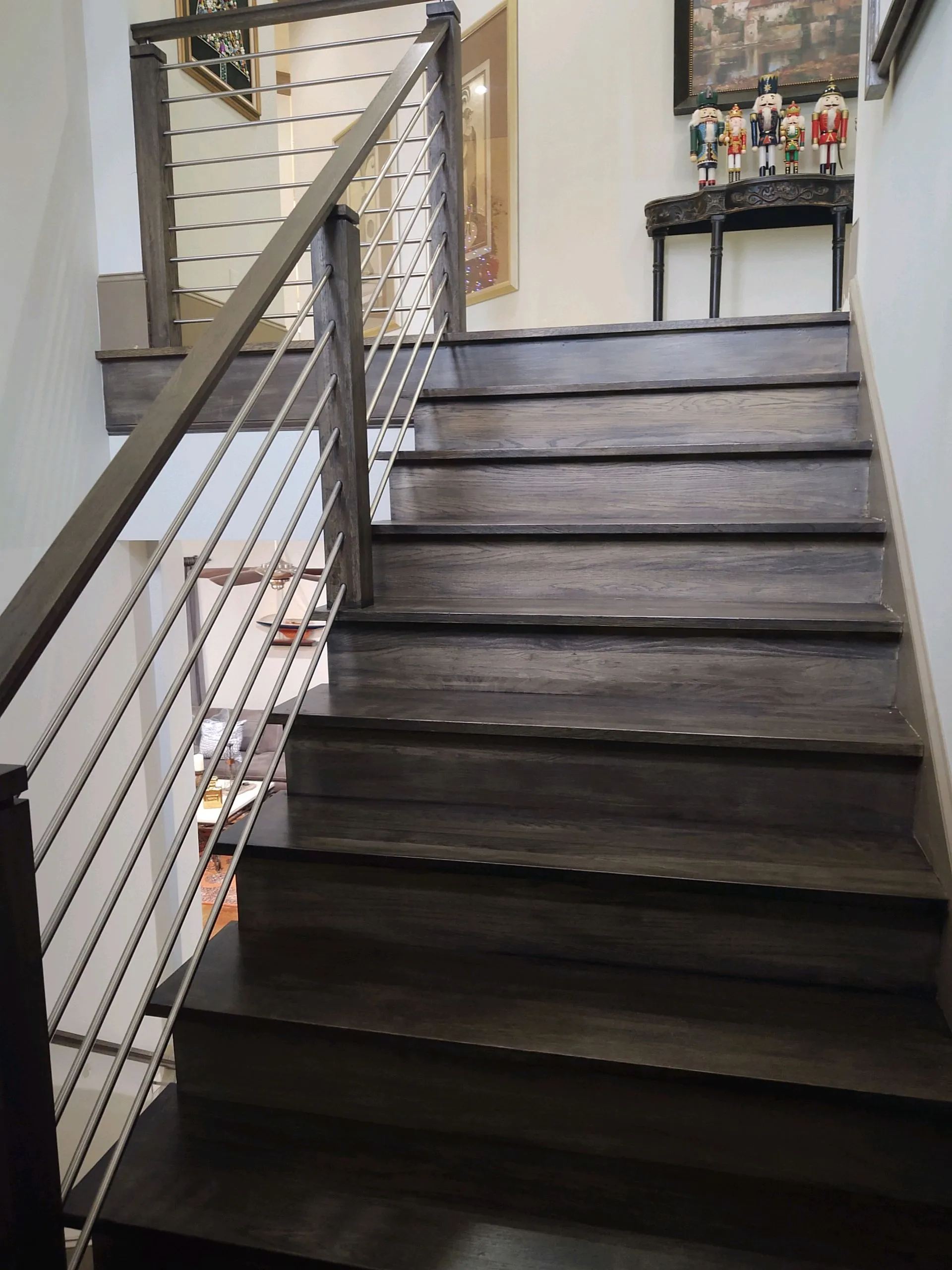 Wooden stairs with metal cable railing, leading upward. The steps are dark brown.