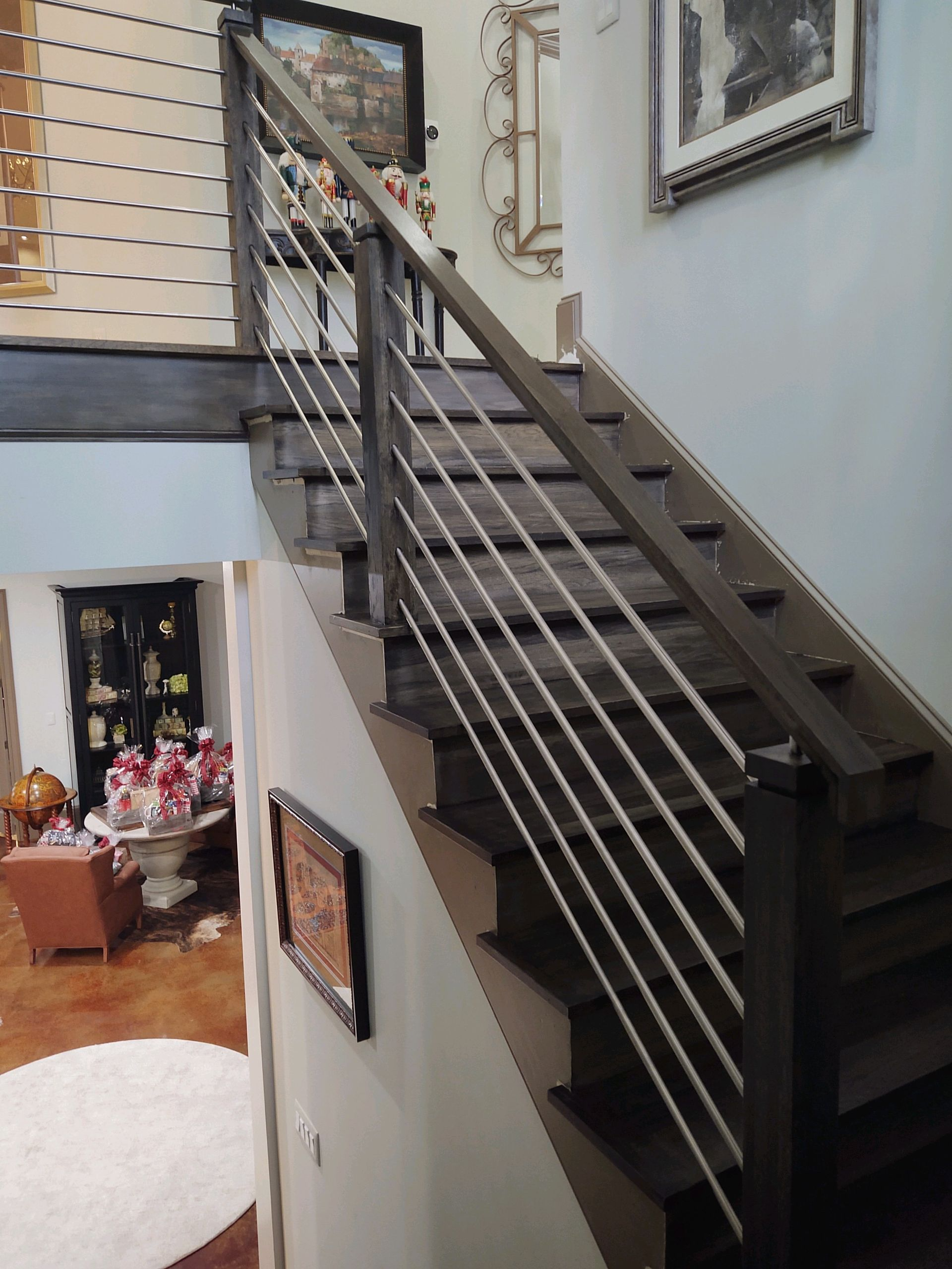 Staircase with dark wooden steps and railing, featuring horizontal steel cables. Interior view.