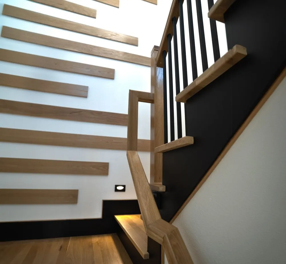 Wooden staircase with black and white accents. Horizontal wood planks on wall.