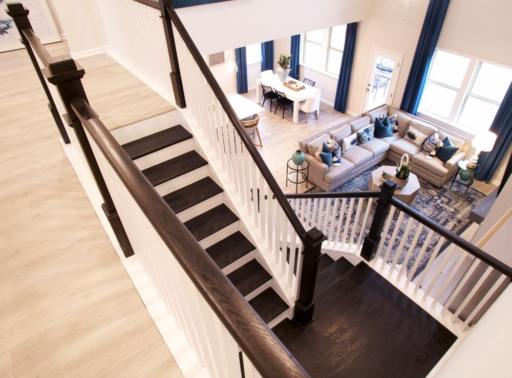 Interior view of a modern home featuring a staircase, living room, and dining area with blue and gray decor.