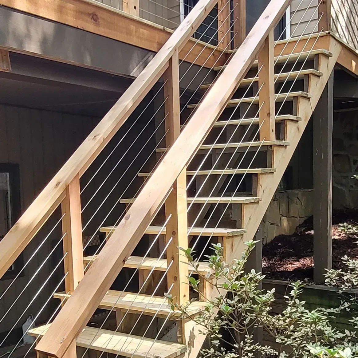 Wooden outdoor staircase with cable railings leads to a deck.