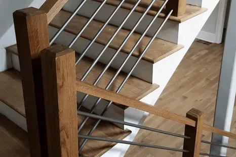 Wooden staircase with horizontal metal railing.