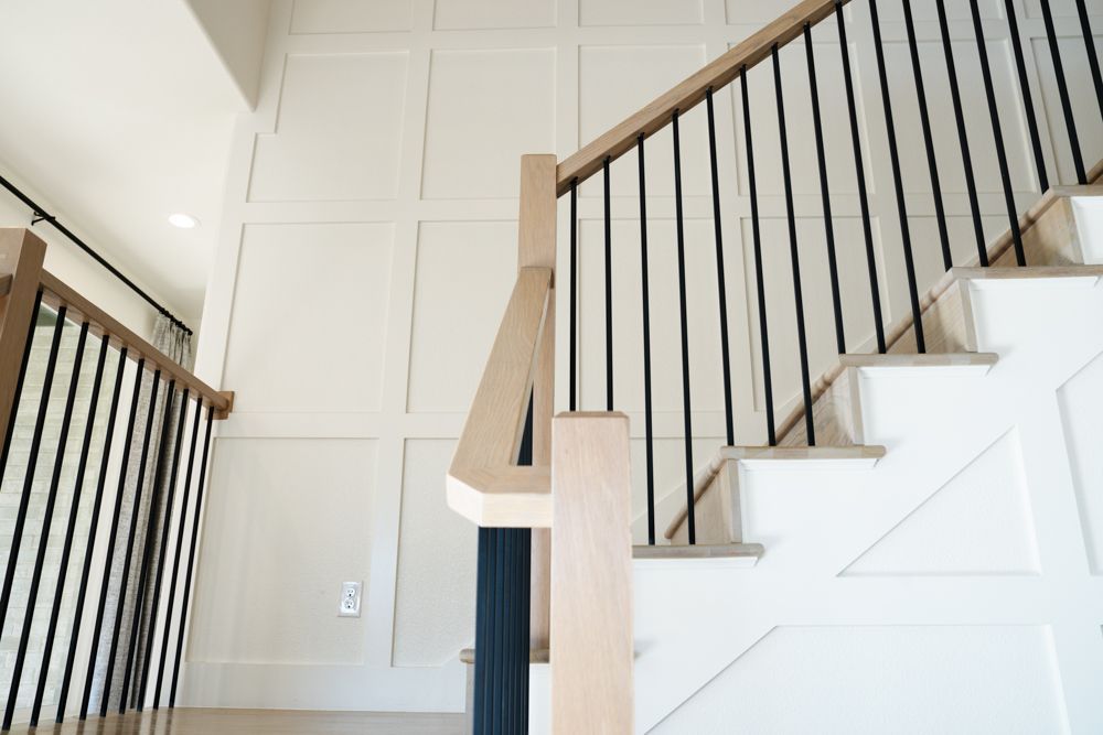 Staircase with wooden handrails and black iron balusters in a home setting.