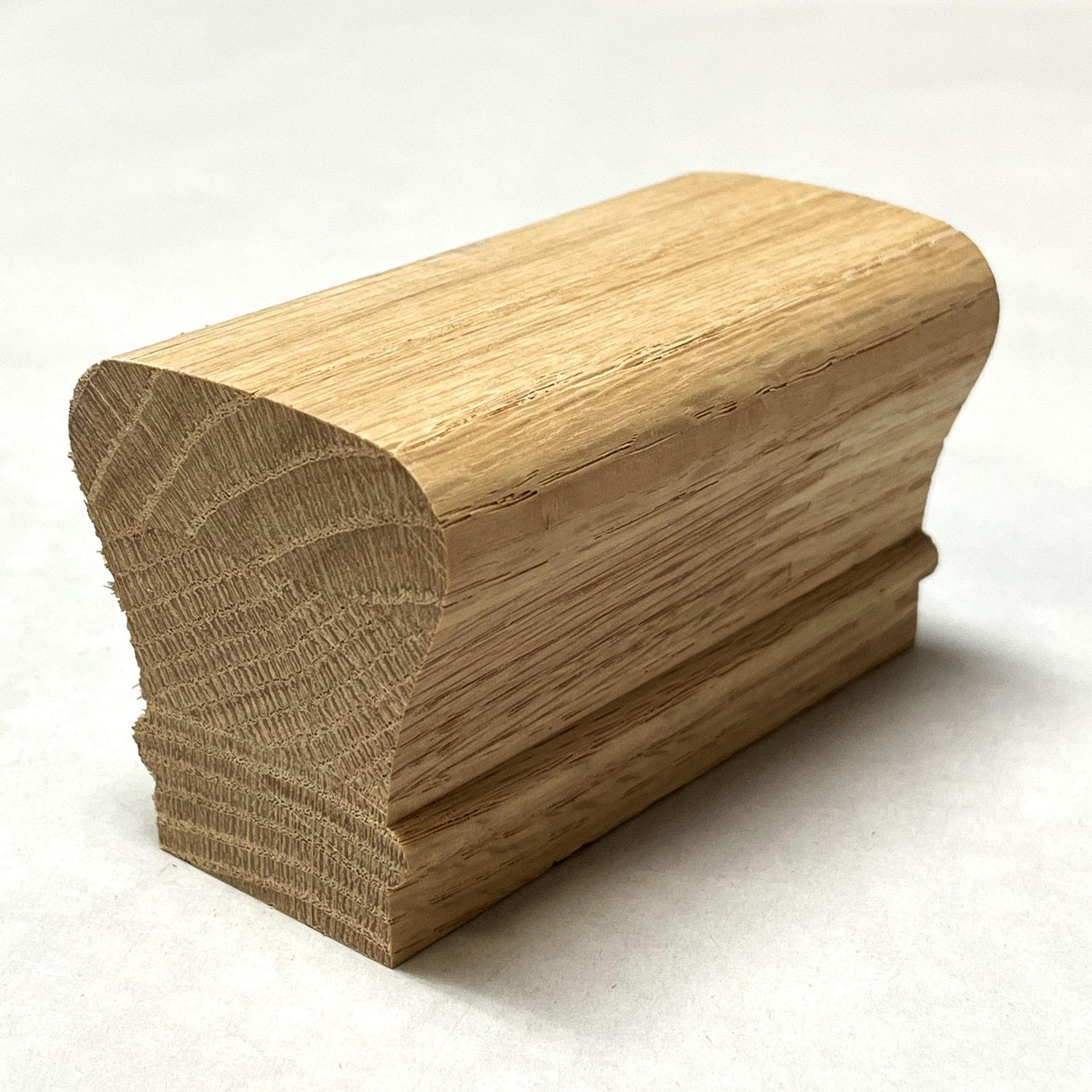 Wooden stair railing cap, natural wood grain, rounded top, grooved lower section.