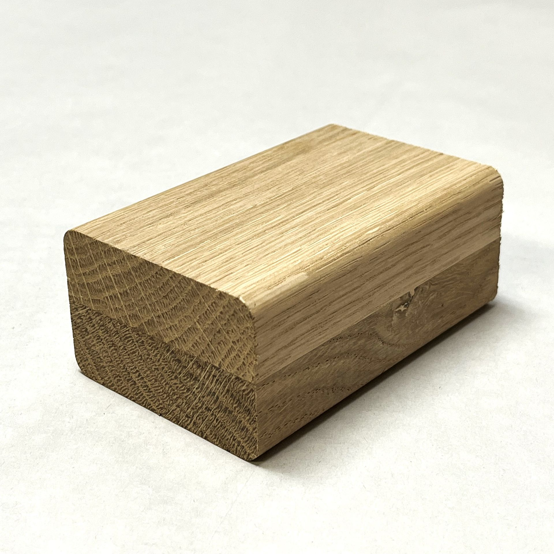Wooden block with rounded top, lying on a white surface.