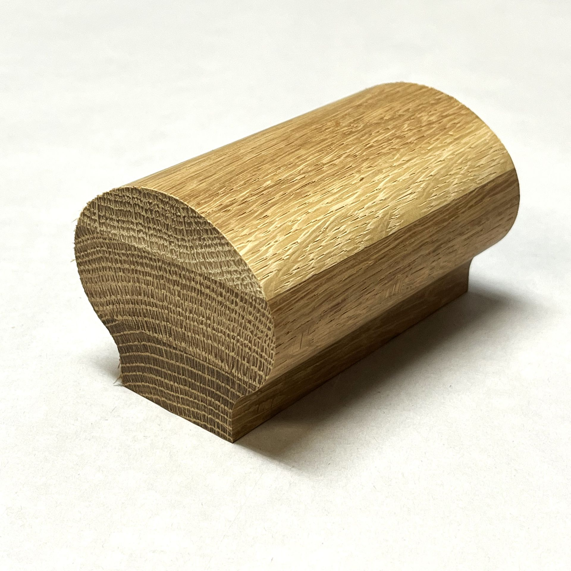 Wooden handrail end piece with a rounded top and a flat base.