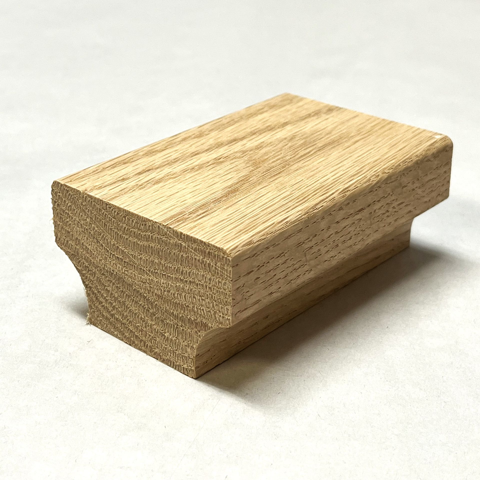 Wooden oak stair handrail newel post on a white surface.