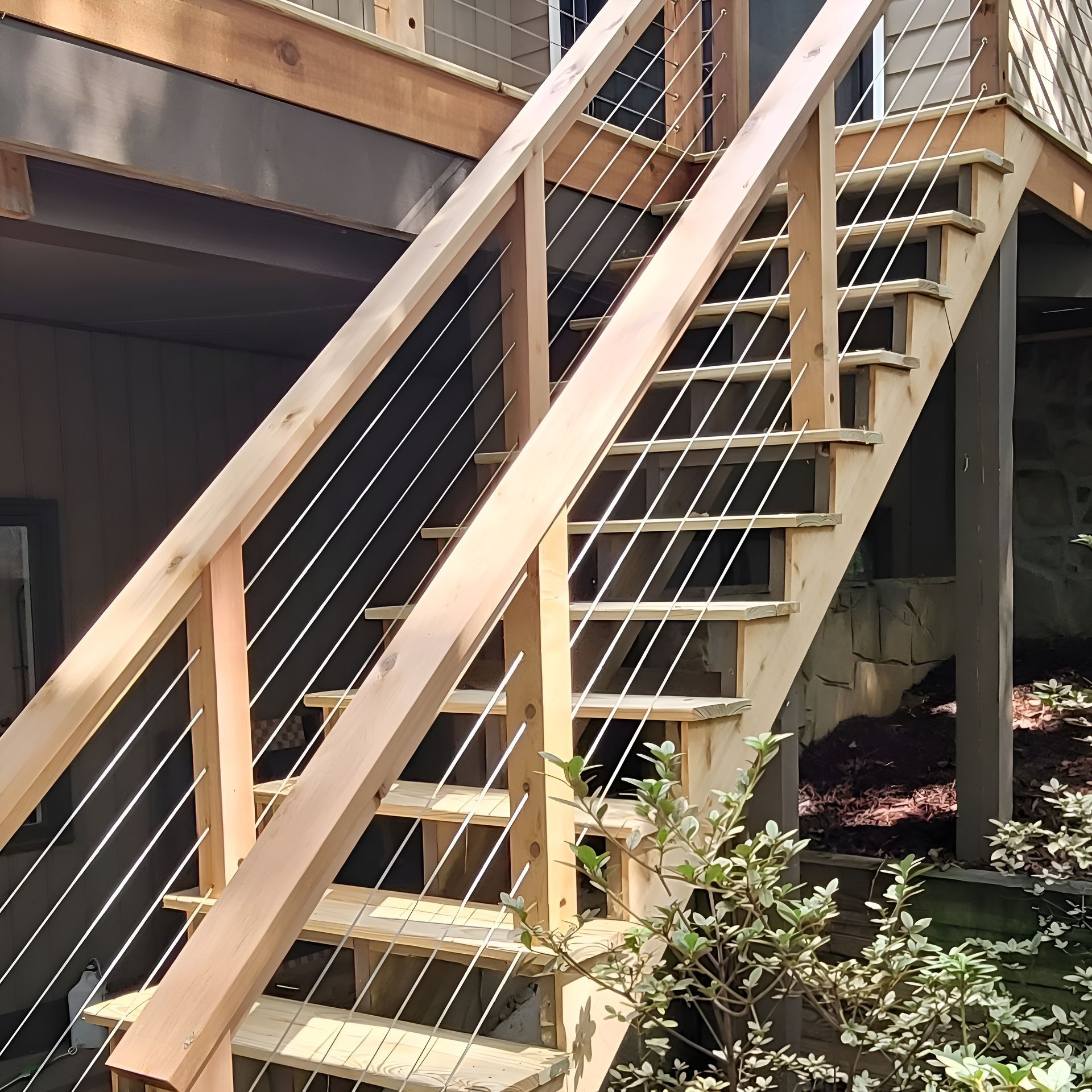 Wooden outdoor stairs with cable railing, leading to a raised deck.