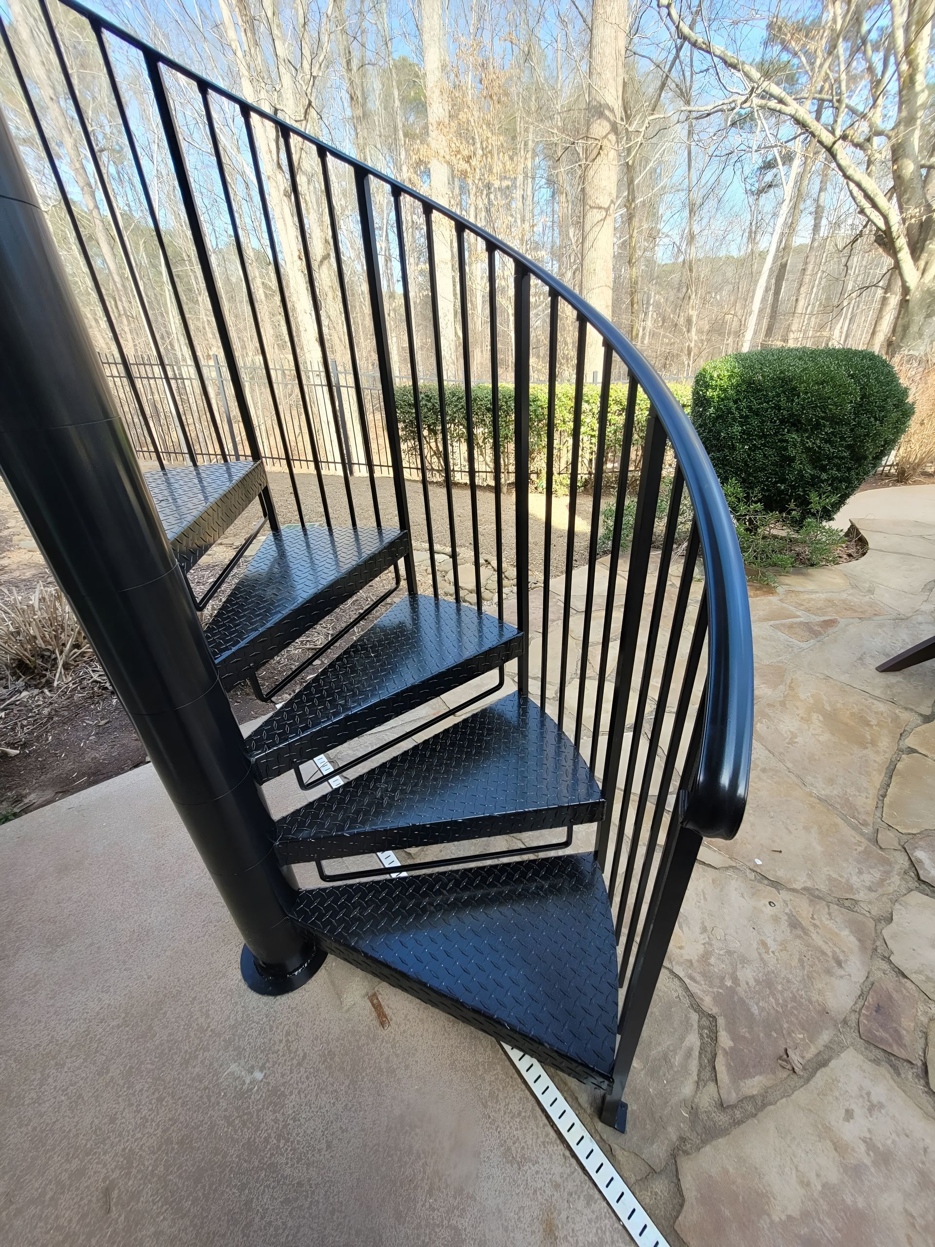 Black spiral staircase outdoors with metal railings.