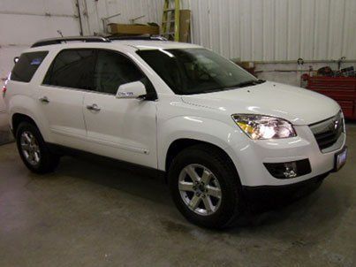 A white suv is parked in a garage next to a garage door.