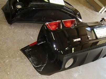 A black car bumper is sitting on a concrete floor.