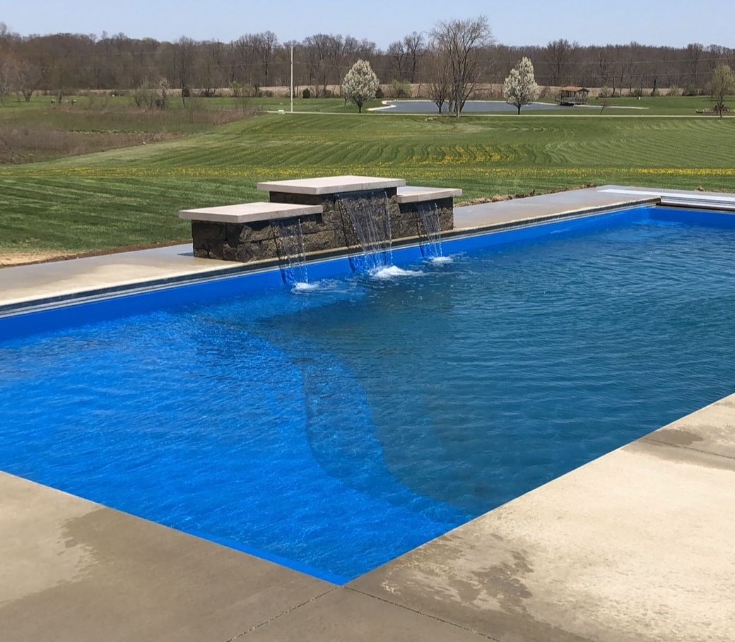 A large blue swimming pool with a waterfall in the middle